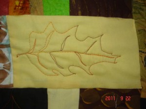 Machine drawn oak leaf in varigated orange thread on yellow