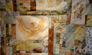 Horizonal quilt of Isis in gold on a cream filed surrounded by other Egyptian images