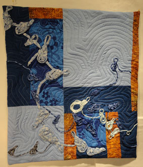 full shot of the quilt showing the frogs on a blue and deep orange background.