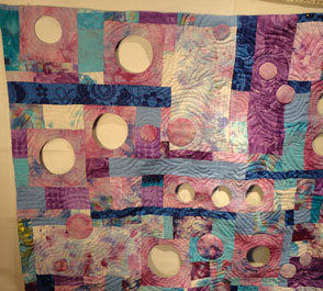 one corner of this blue and pink quilt with the wholes and some of the quiltng
