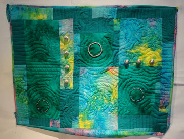 Horizonal quilt in green and yellow with silver baeds