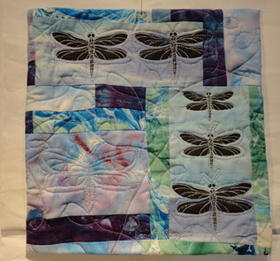 small quilt in pale tones of blue and green with dragon flies printed in black