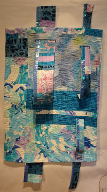 Full shot of turquoise quilt with two long units that thread throug and stick out from the surface