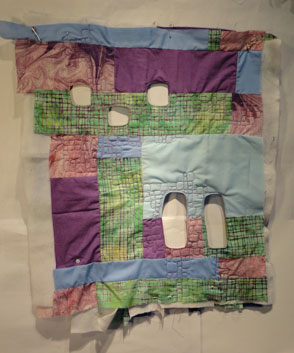 Full shot of the partul quilted purple green and blue quilt. Five wholes in this work 