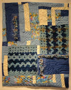 Full shot of completed quilt showing blues, cream 